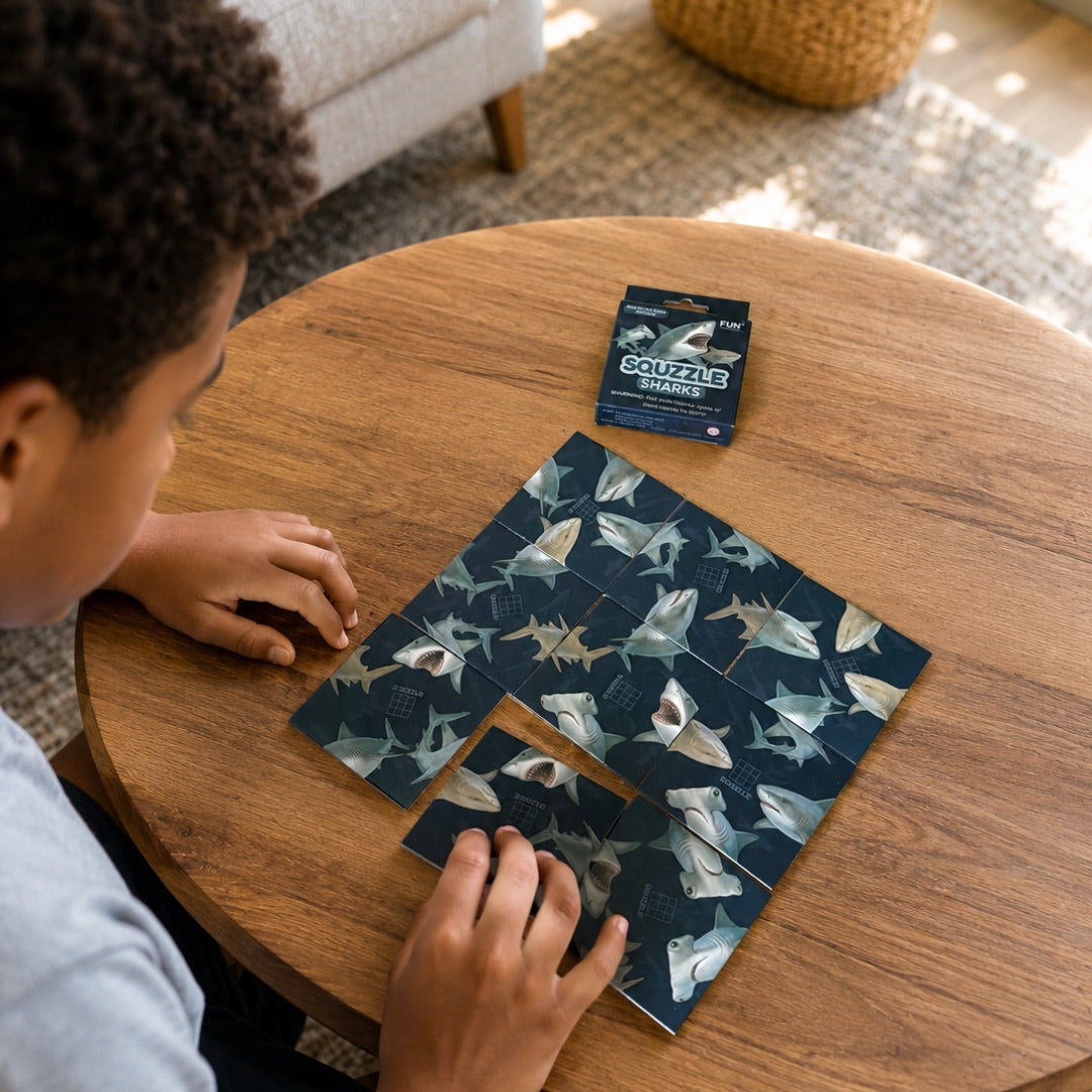 A person arranging nine Sharks Squzzle picture tiles at a table, with the matching box nearby.