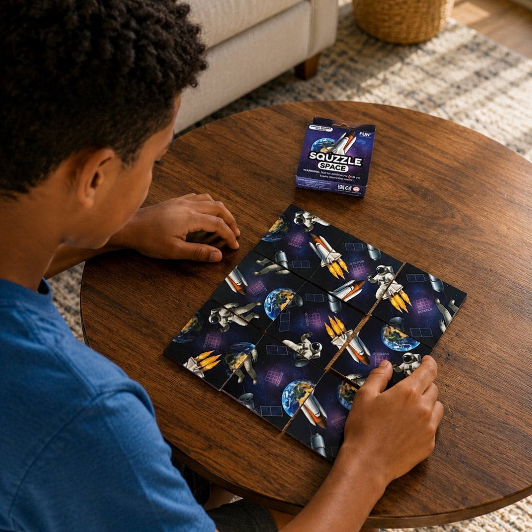 A person arranging nine Space Squzzle picture tiles at a table, with the matching box nearby.